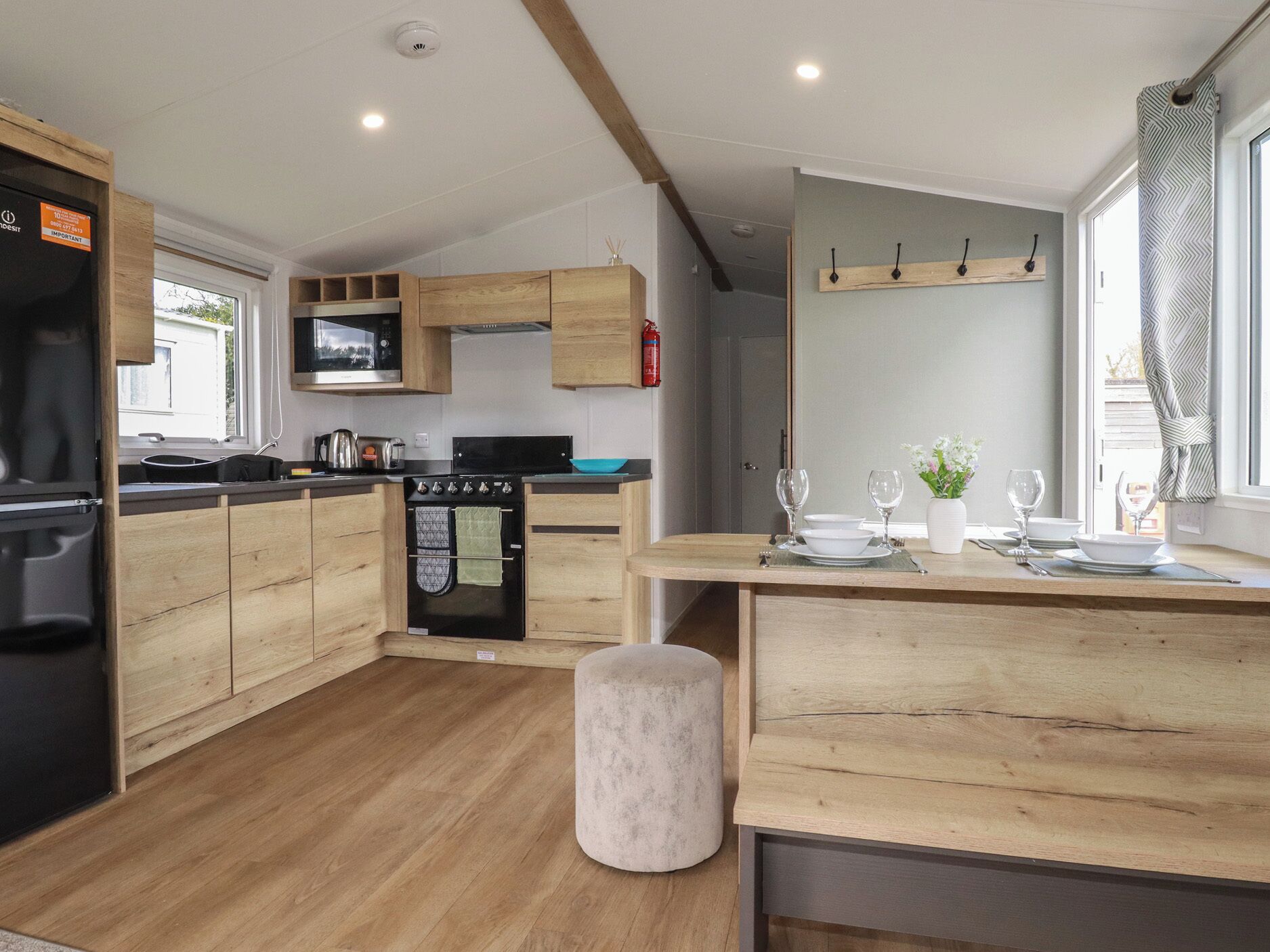 Una cocina moderna con armarios de madera, horno integrado y una zona de comedor con una mesa dispuesta para dos personas.