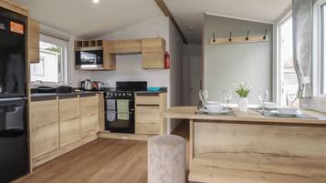 Una cocina moderna con armarios de madera, horno integrado y una zona de comedor con una mesa dispuesta para dos personas.