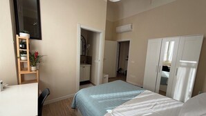Una camera da letto con un letto, una scrivania, un armadio e uno specchio.
