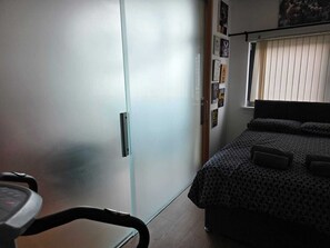 Ein Schlafzimmer mit Bett, Kleiderschrank und Laufband.