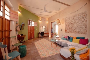 A cozy living room with a sofa, chairs, a coffee table, a TV, and a large wall art piece. - Cozy, colorful house Casa Sirena (Mérida)
