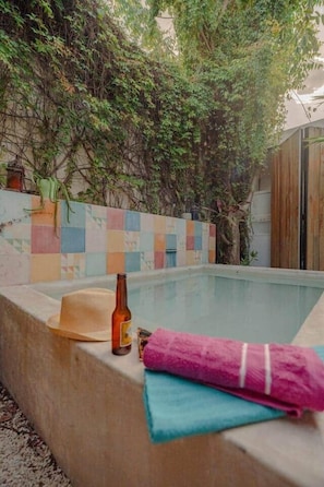 A swimming pool with a tiled wall, a bottle, and a hat. - Cozy, colorful house Casa Sirena (Mérida)