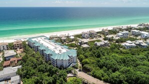 Eine Luftaufnahme eines Küstenresorts mit Strandvillen, einem großen Gebäude mit Gründach und freiem Blick auf den Ozean.