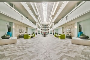 Eine großzügige Lobby mit hoher Decke, mehreren Etagen und einer zentralen Sitzecke.