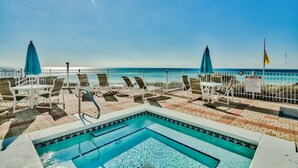 Ein Poolbereich mit Liegestühlen und Sonnenschirmen, ein Pool mit gefliestem Rand und freier Sicht auf den Ozean.