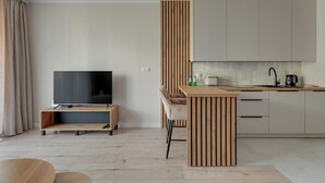 Una sala de estar moderna con un televisor de pantalla plana, mueble de entretenimiento de madera y un comedor con mesa y sillas de madera.