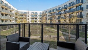 Un moderno edificio de apartamentos con balcones, mobiliario exterior y vistas despejadas del entorno.