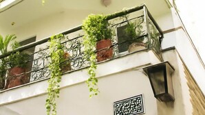 Un edificio de varios pisos con balcones decorados con plantas en macetas y un farol tradicional.