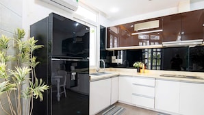 Una cocina moderna con un refrigerador negro, armarios blancos, un lavaplatos y un ventanal.