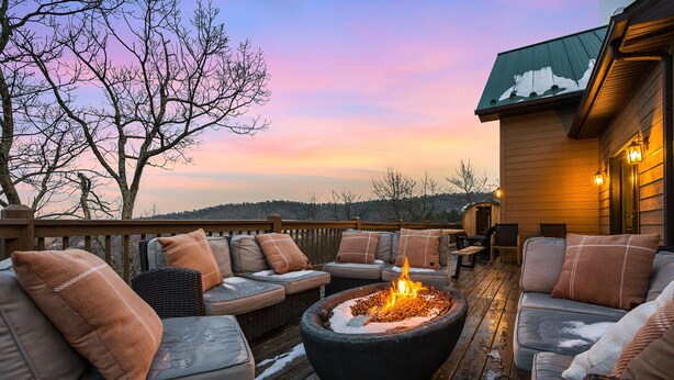 Eine Terrasse mit Sitzgelegenheiten im Freien, einem Feuerkorb und Blick auf die Landschaft.