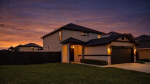 Une maison à deux étages avec un garage, une véranda et une pelouse bien entretenue.