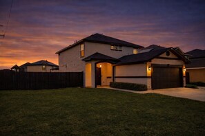 A two-story house with a garage, a covered porch, and a well-maintained lawn. - Spacious Laredo Home w/ Fire Pit, Playground & Backyard (Laredo)
