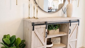 Un meuble en bois avec un miroir, des bougeoirs et une pancarte de bienvenue.
