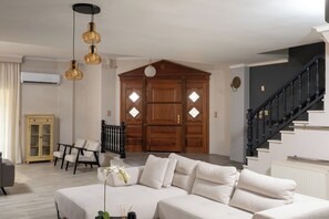 Una sala de estar con sofá, sillas, un aparador y una escalera.