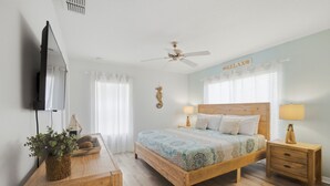 Ein Schlafzimmer mit einem Bett, Nachttischen, einem Deckenventilator und einem an der Wand befestigten Fernseher.