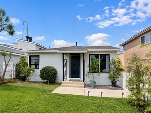 Ein eingeschossiges Haus mit Veranda, kleinem Vorgarten und blauem Himmel.