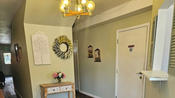 A hallway with a wooden floor, a white door, and a wall-mounted light fixture.