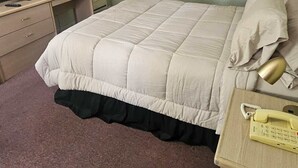 A bedroom with a bed, a television, a lamp, and a telephone.