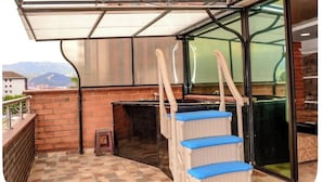 Un espace extérieur abrité, doté d’un barbecue, offrant une vue sur la ville et comprenant un escalier menant à un niveau supérieur.
