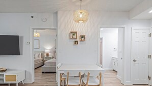 Een moderne woonkamer met een eettafel, stoelen, een televisie en een bijzondere hanglamp.