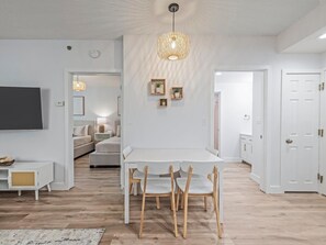 A modern living room with a dining table, chairs, a TV, and a unique hanging light fixture. - Close to Epic Universe & Universal - free parking (Orlando)