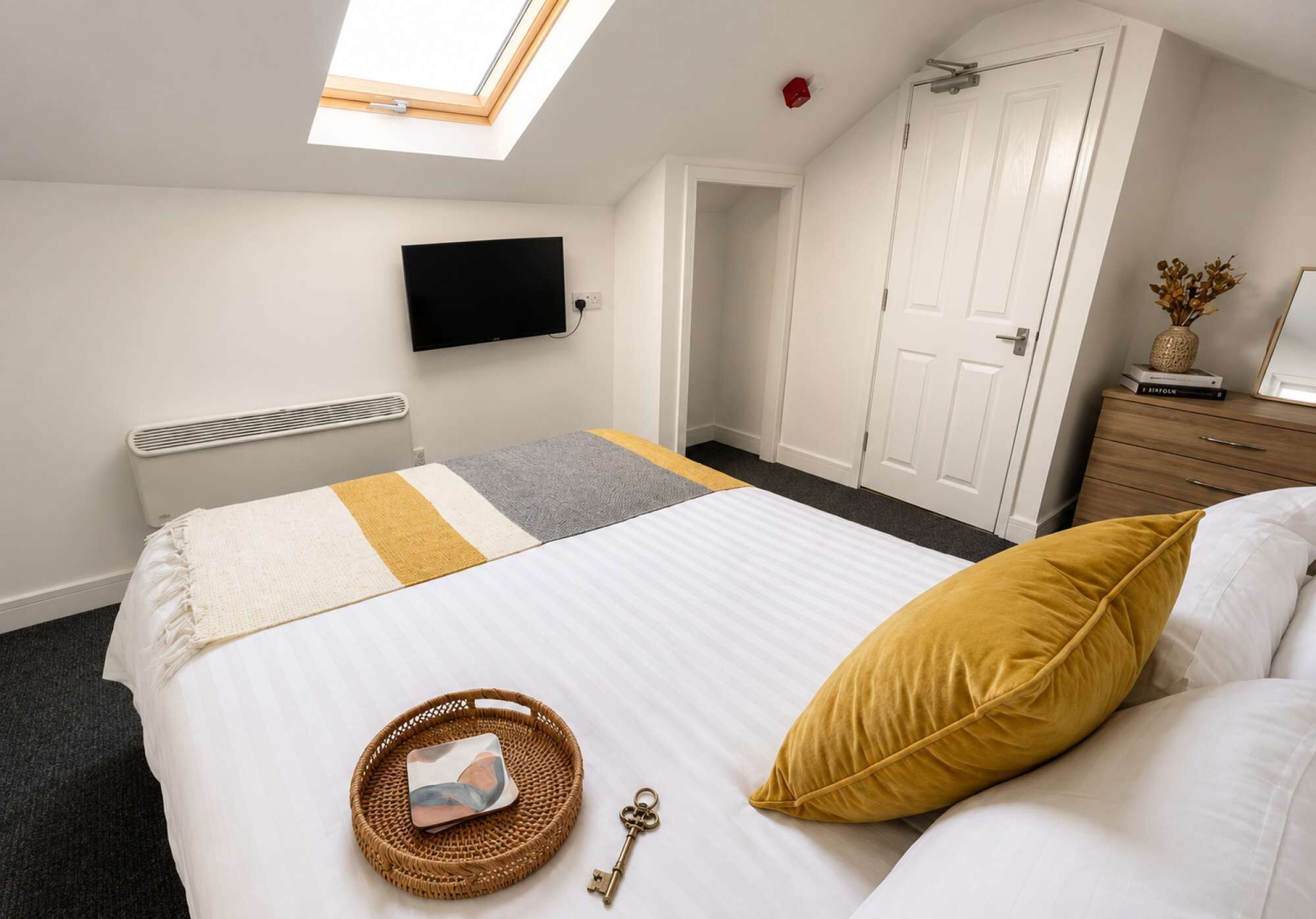 Une chambre à coucher comprenant un lit, une télévision, une armoire et un puits de lumière.