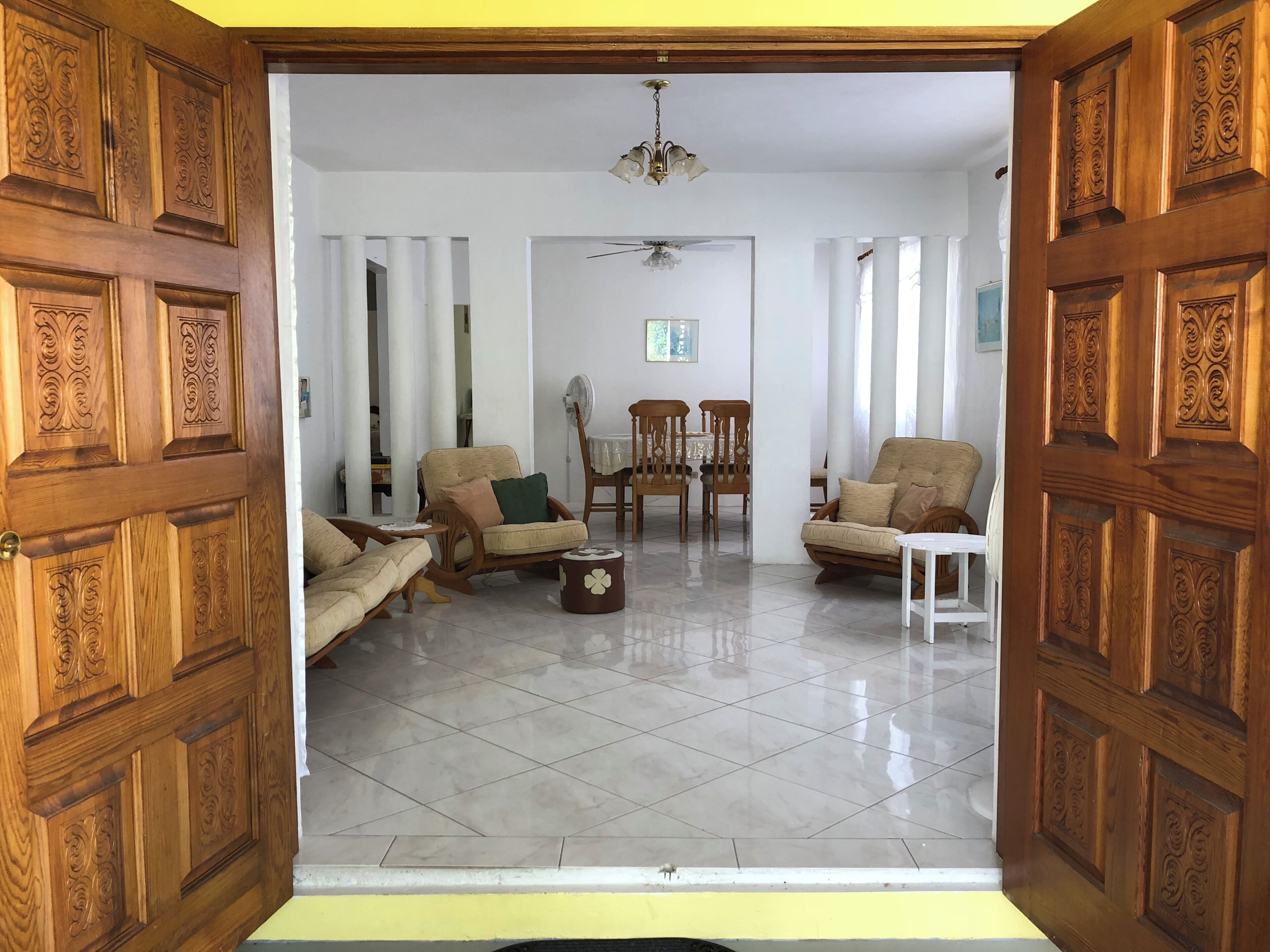Un salón espacioso con techo alto, ventilador de techo y comedor con sillas y una mesa.