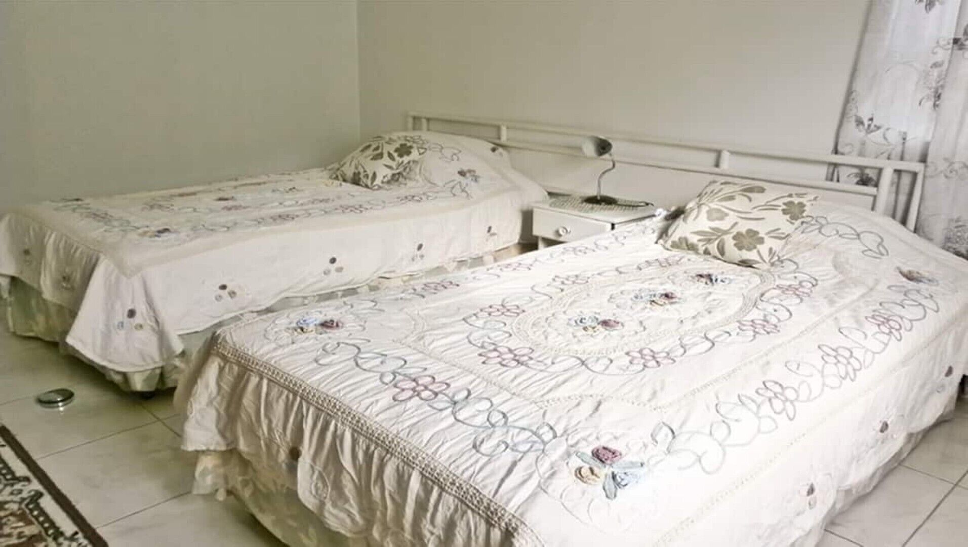 Un dormitorio con dos camas individuales, una mesita de noche y una mesilla.