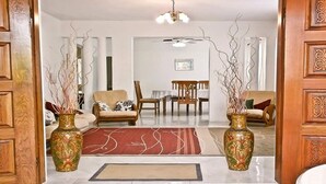 Ein Wohnzimmer mit einer Couch, Sesseln, einem Couchtisch und zwei dekorativen Vasen.