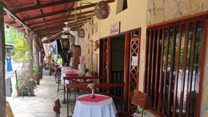 An outdoor café with tables and chairs, a ceiling fan, stone walls, and a sign for 'Bonaventura.' - Hotel Museo Xibalba (Palenque)