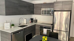 A modern kitchen with grey cabinets, stainless steel appliances, a sink, and a table with a bowl of lemons. - Modern studio in the heart of Downtown/Brickell Miami. Walk to Brickell. (Miami)