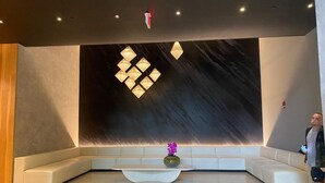 A modern lobby with a large wall-mounted light fixture, a seating area, and a vase with flowers. - Modern studio in the heart of Downtown/Brickell Miami. Walk to Brickell. (Miami)