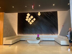Eine moderne Lobby mit einer großen Wandleuchte, einer Sitzecke und einer Blumenvase.