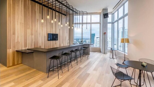 A modern kitchen with a bar area, bar stools, and a large window with a city view. - Modern studio in the heart of Downtown/Brickell Miami. Walk to Brickell. (Miami)