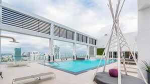 A rooftop pool area with a view of the city skyline, lounge chairs, and a swing chair. - Modern studio in the heart of Downtown/Brickell Miami. Walk to Brickell. (Miami)