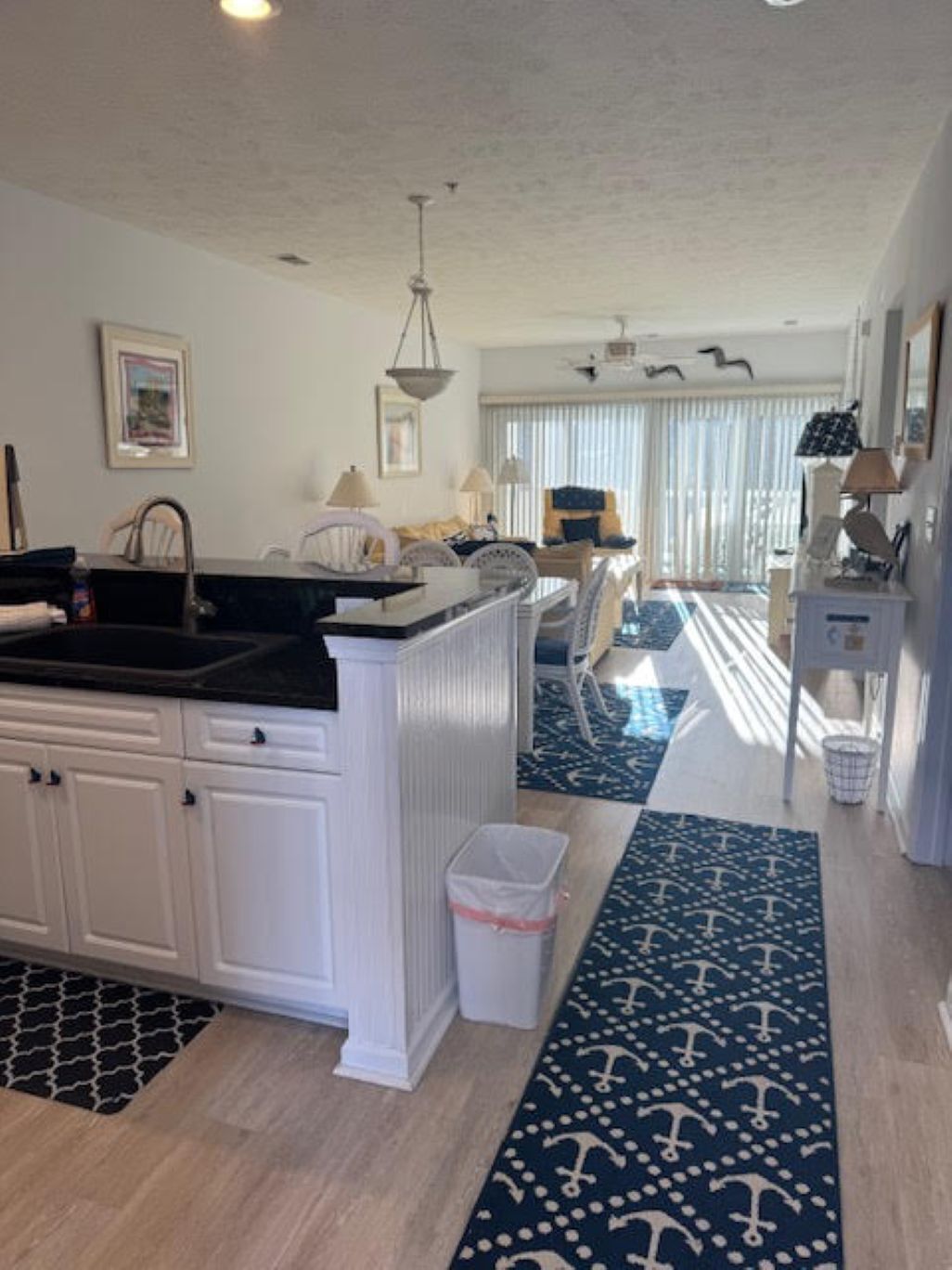 A kitchen with white cabinets, a black countertop, and a hanging light fixture.