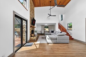 A spacious living area with a fireplace, a sofa, a staircase, and a view of the outdoors. - Stonewood Escape 4BR Fireplace Near Hard Rock (Hollywood)