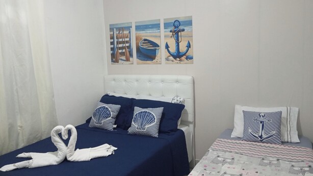 Un dormitorio con una cama, una mesita de noche, aire acondicionado instalado en la pared y decoración náutica en las paredes.
