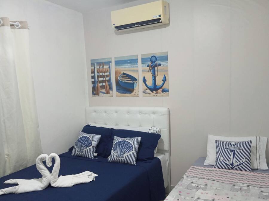 Ein Schlafzimmer mit einem Bett, einem Nachttisch, einer Wand-Klimaanlage und Wandbildern zum Thema Seefahrt.
