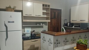 Una cocina con armarios blancos, un refrigerador, un microondas y una cafetera.