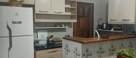 A kitchen with white cabinets, a refrigerator, a microwave, and a coffee maker.