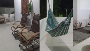 Una habitación con sillones de mimbre, una hamaca y una pequeña mesa.
