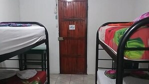 A room with bunk beds, a wooden door, and a ceiling fan. - downtown montezuma hostal  (Montezuma)