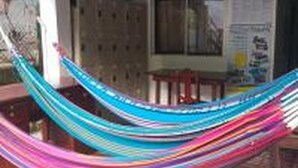 A hammock on a tiled patio with a building in the background. - downtown montezuma hostal  (Montezuma)