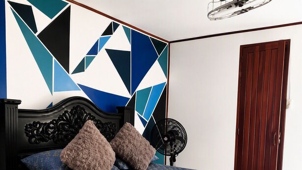 A bedroom with a bed, pillows, a fan, and a wooden door. - downtown montezuma hostal  (Montezuma)