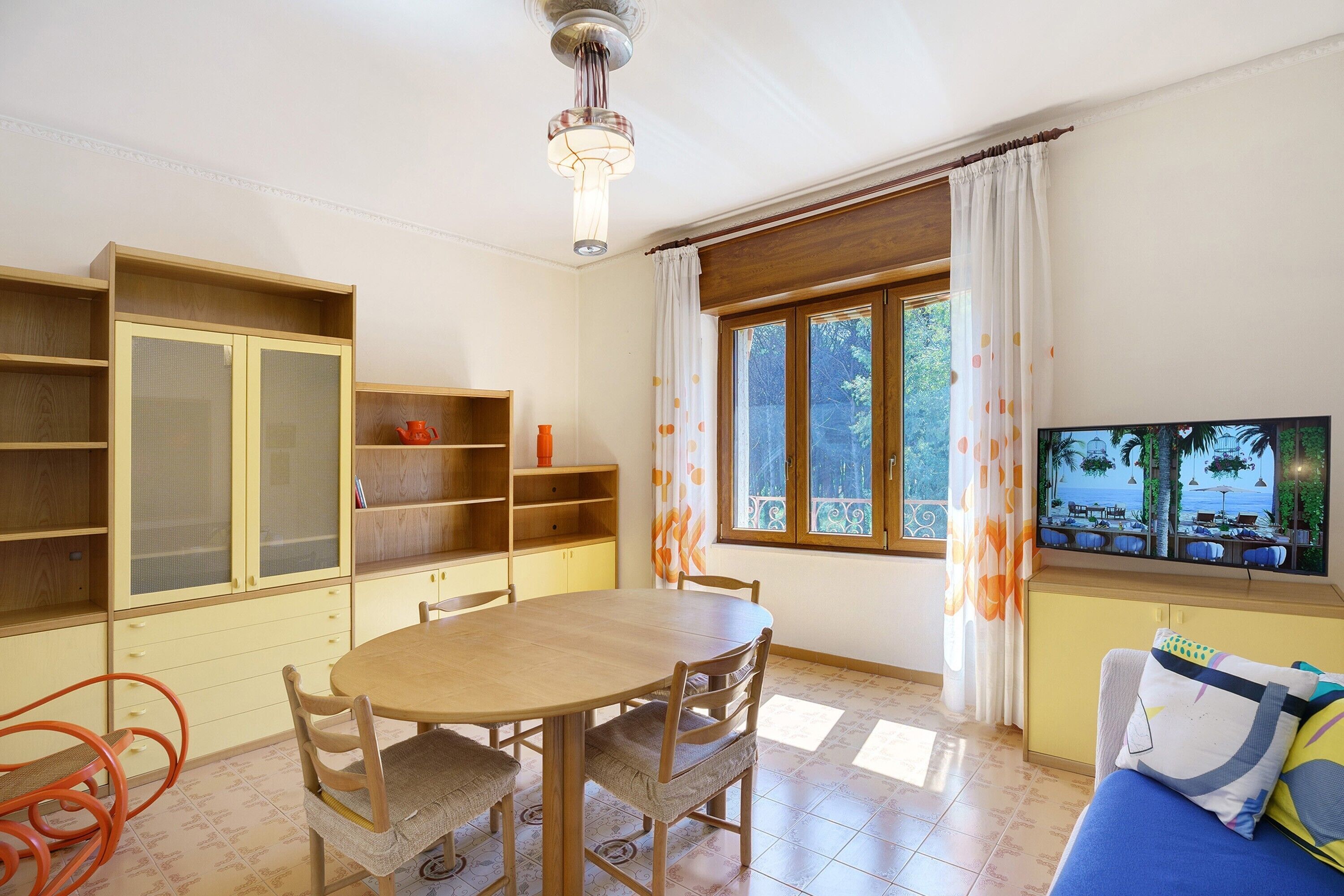 A dining area with a round table, chairs, and a television on a wall.