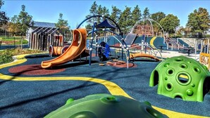 Un parque infantil con toboganes, estructuras para escalar y una casita verde.