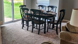 Un coin repas avec une table et des chaises, une lampe, et une vue par la fenêtre.
