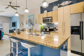 A modern kitchen with granite countertops, stainless steel appliances, and a blue accent wall. - Beachside Condo w/ Pools, Hot Tubs & Balcony (South Padre Island)