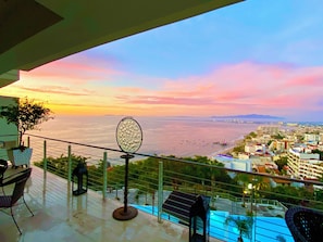 Ein Balkon mit Blick auf das Meer, einen Pool und eine Stadtansicht.